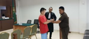 Advokat Hermanto Tambunan mendampingi Marianto alias Along yang sedang dipasangkan borgol oleh petugas Kejaksaan Negeri Batam. (Sumber foto: JP – BATAMPENA.COM)