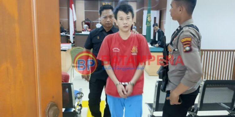 Terdakwa Selamat alias Ferry alias Along digiring oleh pengawal tahanan dari Kejari Batam, Rizal. (Sumber foto: JP - BatamPena.com)